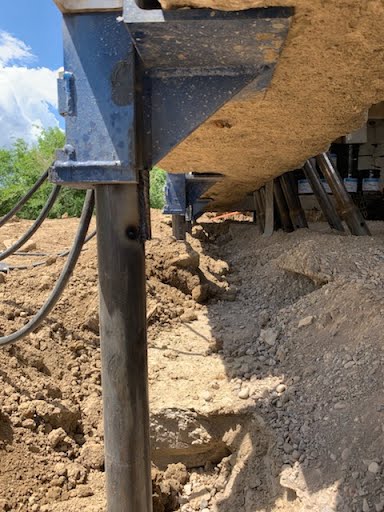 Close-up of a push pier bracket transferring the weight of a home during foundation lifting