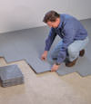 Contractors installing basement subfloor tiles and matting on a concrete basement floor in Clifton, Colorado