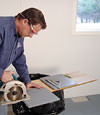 installing a waterproof vapor barrier on a basement floor to prepare for basement carpeting in a Montrose home